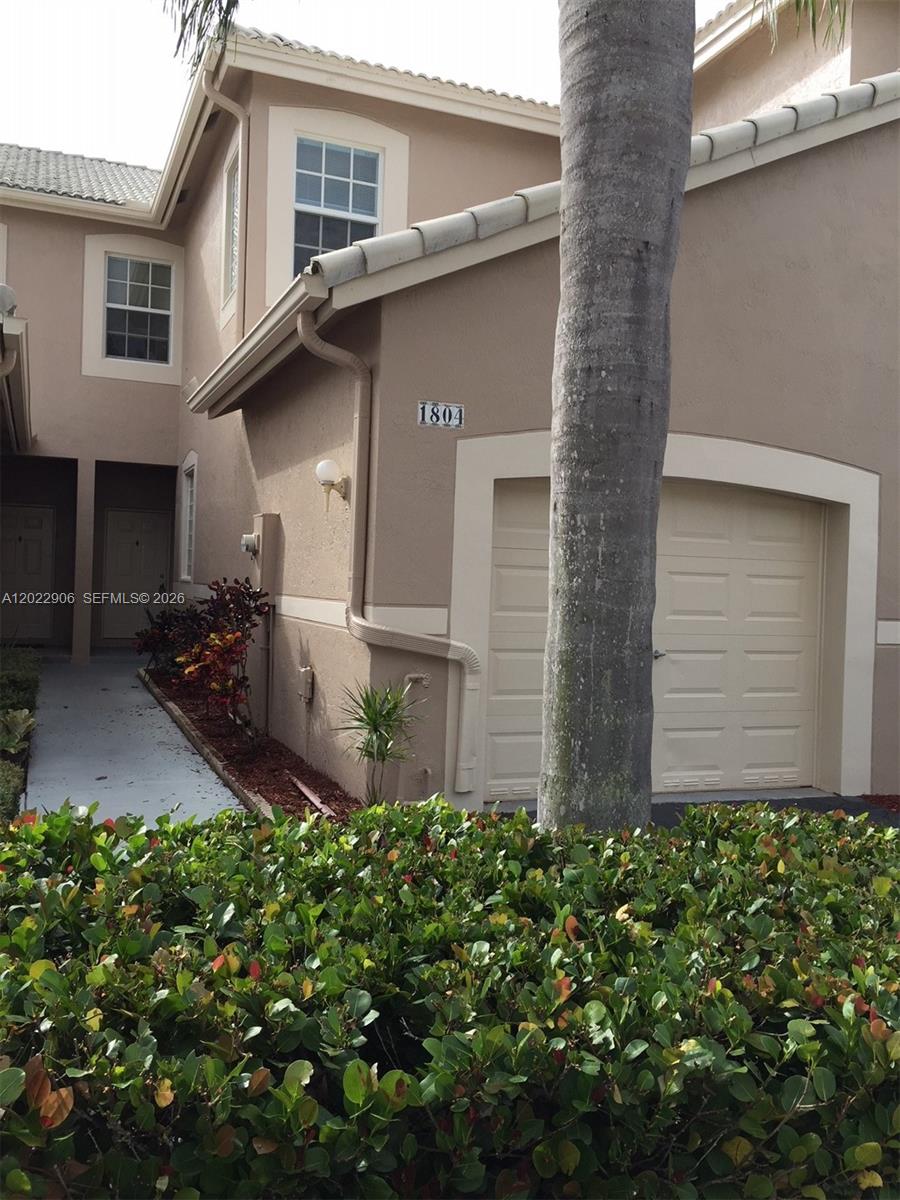 A beige two-story townhouse exterior features a single-car garage and a palm tree — 1804 Salerno Cir # 1804, Weston FL 33327, WESTON, FL