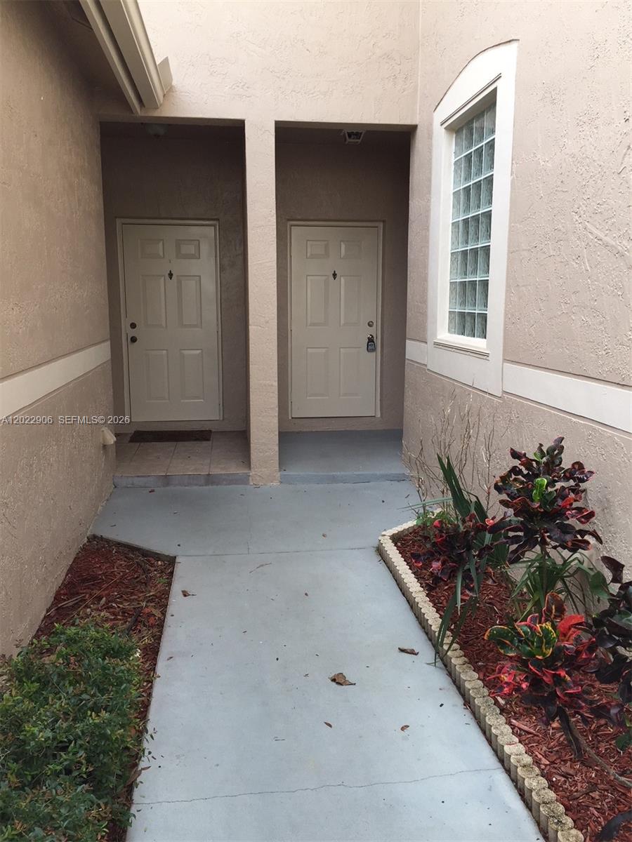 A concrete walkway leads to two adjacent beige entry doors with a glass block window — 1804 Salerno Cir # 1804, Weston FL 33327, WESTON, FL