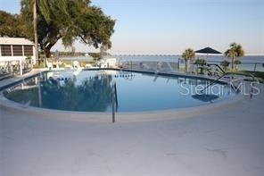 A swimming pool overlooks a body of water with a bridge in the distance — 585 SKY HARBOR DRIVE UNIT 326, CLEARWATER, FL