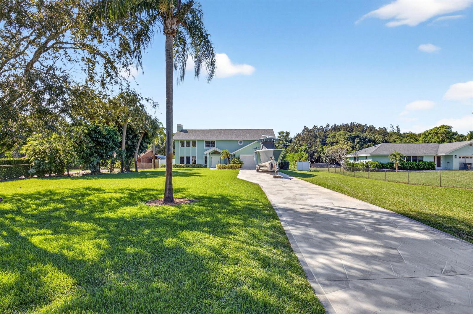 A two-story light green house with a boat on a trailer in the driveway — 6701 Hillside Lane, Lake Worth FL 33462, LAKE WORTH, FL