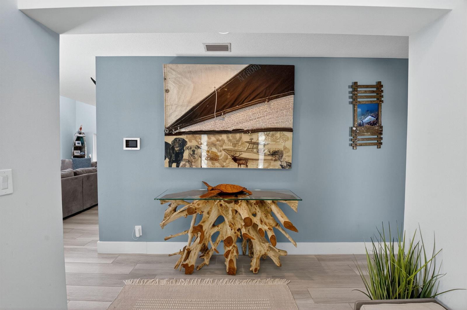 A blue wall features a large nautical-themed painting above a driftwood console table — 6701 Hillside Lane, Lake Worth FL 33462, LAKE WORTH, FL