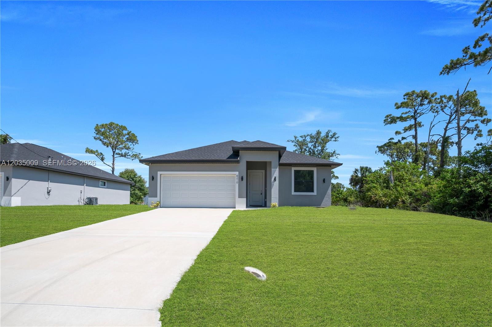 A single-story gray house with a white garage door sits on a grassy lot — 6210 Forest Court, La Belle FL 33935, LA BELLE, FL