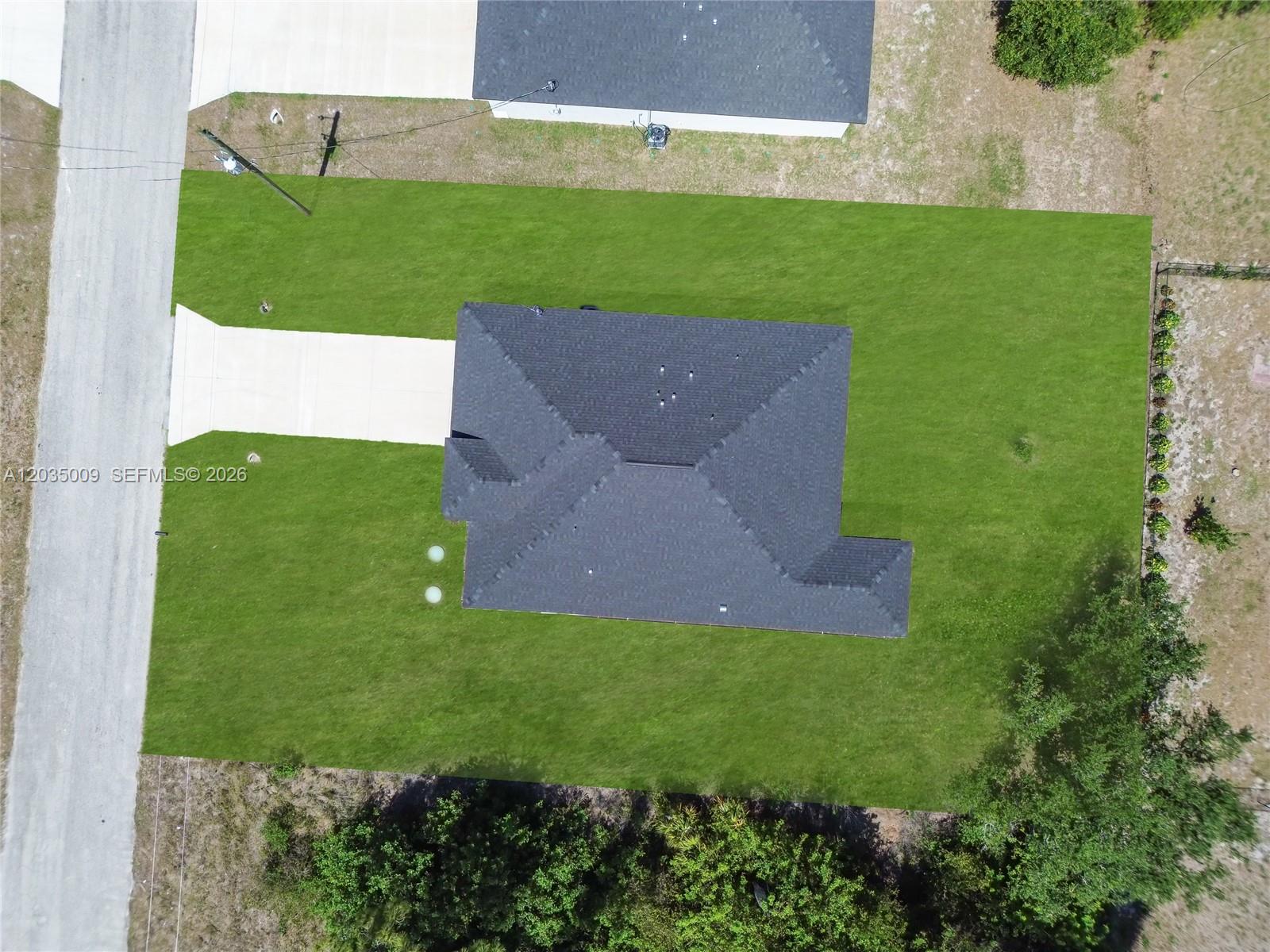 An aerial view shows a house with a dark roof centered on a grassy lot — 6210 Forest Court, La Belle FL 33935, LA BELLE, FL