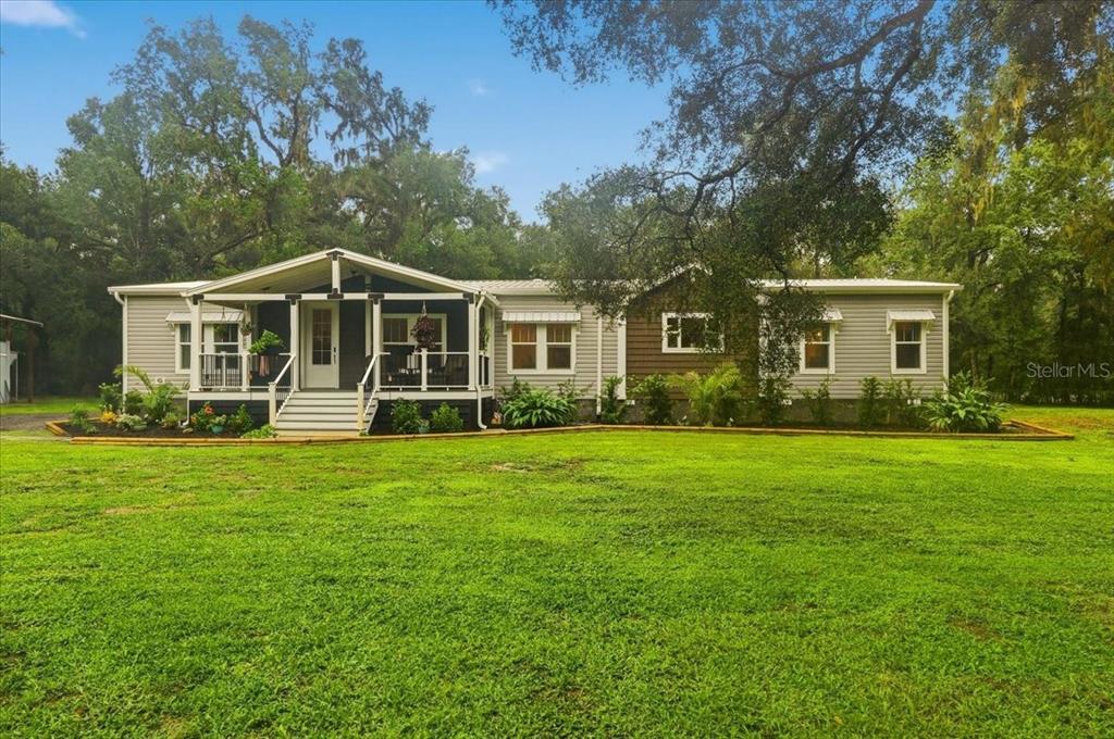 A single-story manufactured home with a covered front porch sits on a grassy lawn — 22256 CHERATON ROAD, BROOKSVILLE, FL