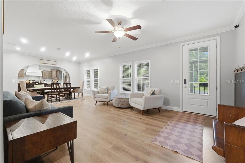 This open-concept living and dining area features light wood flooring, neutral walls, and a ceiling fan — 22256 CHERATON ROAD, BROOKSVILLE, FL