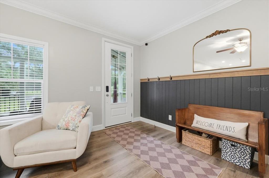 An entryway features a white armchair, a wooden bench with a pillow, and dark wainscoting — 22256 CHERATON ROAD, BROOKSVILLE, FL