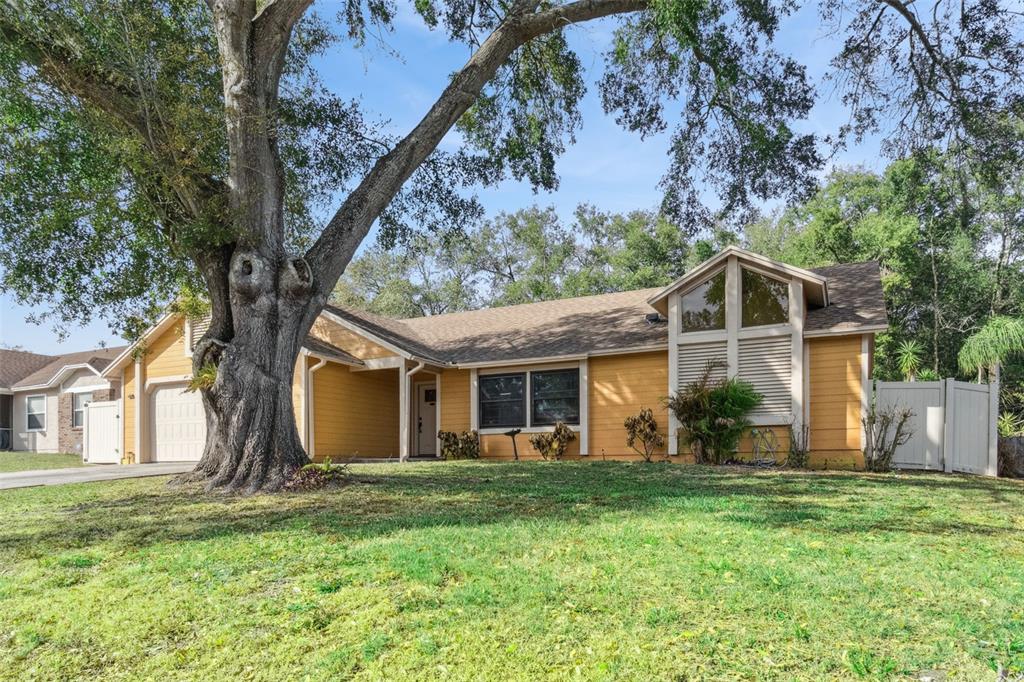 A yellow single-story house with a large oak tree in the front yard — 6815 CRESCENT RIDGE ROAD, ORLANDO, FL
