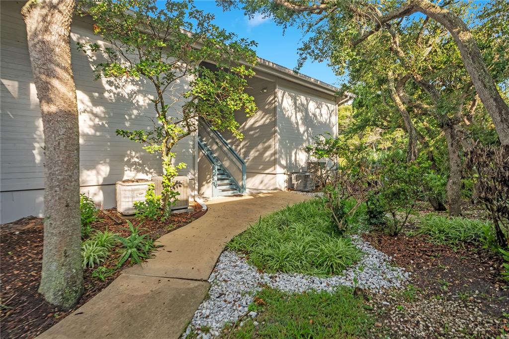 A concrete walkway leads to an outdoor staircase beside a light-colored building with landscaping — 4303 SEA MIST DRIVE UNIT 224, NEW SMYRNA BEACH, FL
