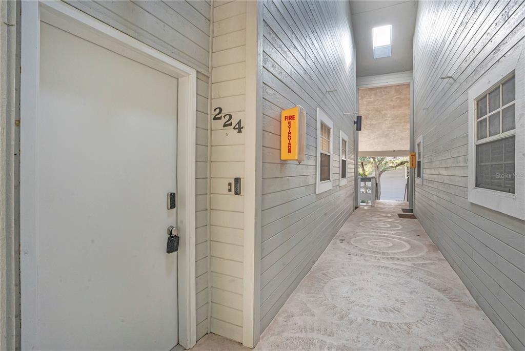 A narrow outdoor walkway leads to a white door marked with the number 224 — 4303 SEA MIST DRIVE UNIT 224, NEW SMYRNA BEACH, FL