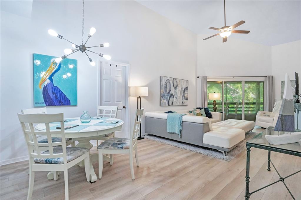 A bright living and dining area features light wood floors, vaulted ceilings, and coastal decor — 4303 SEA MIST DRIVE UNIT 224, NEW SMYRNA BEACH, FL