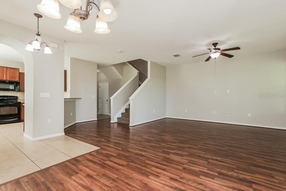 An open-concept living area features wood-look flooring, a staircase, and a kitchen with tile floors — 5511 KINGLETHILL DRIVE, LITHIA, FL