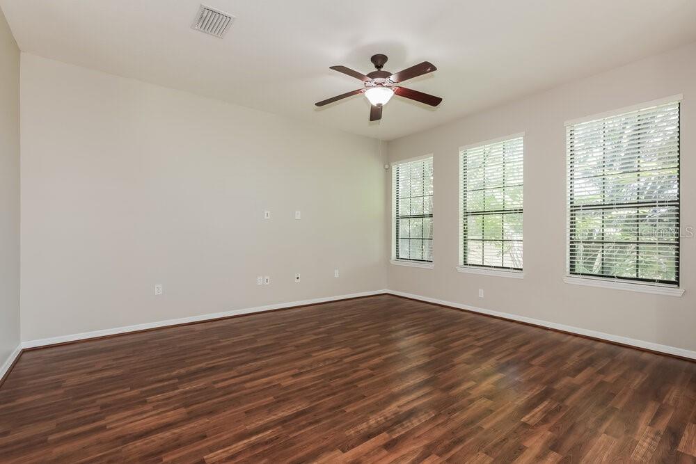 An empty room with wood-look flooring, a ceiling fan, and three windows with blinds — 5511 KINGLETHILL DRIVE, LITHIA, FL