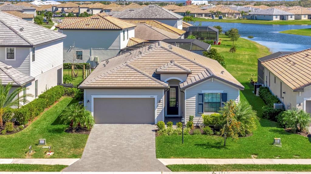 A single-story suburban house with a tan tile roof and a paved driveway — 5317 CORAL REEF WAY, BRADENTON, FL