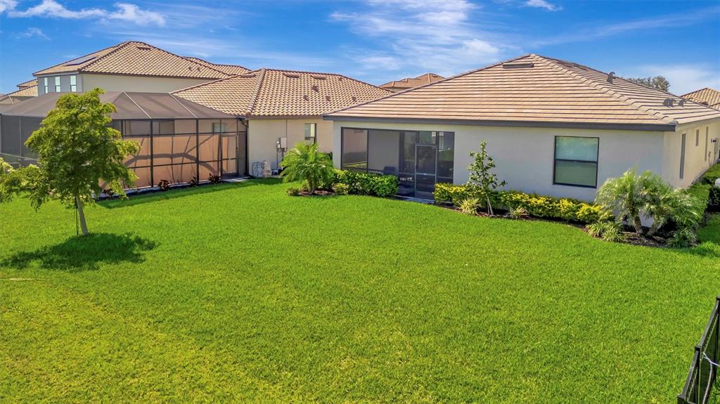 The backyard features a green lawn, a screened-in patio, and a single-story house exterior — 5317 CORAL REEF WAY, BRADENTON, FL