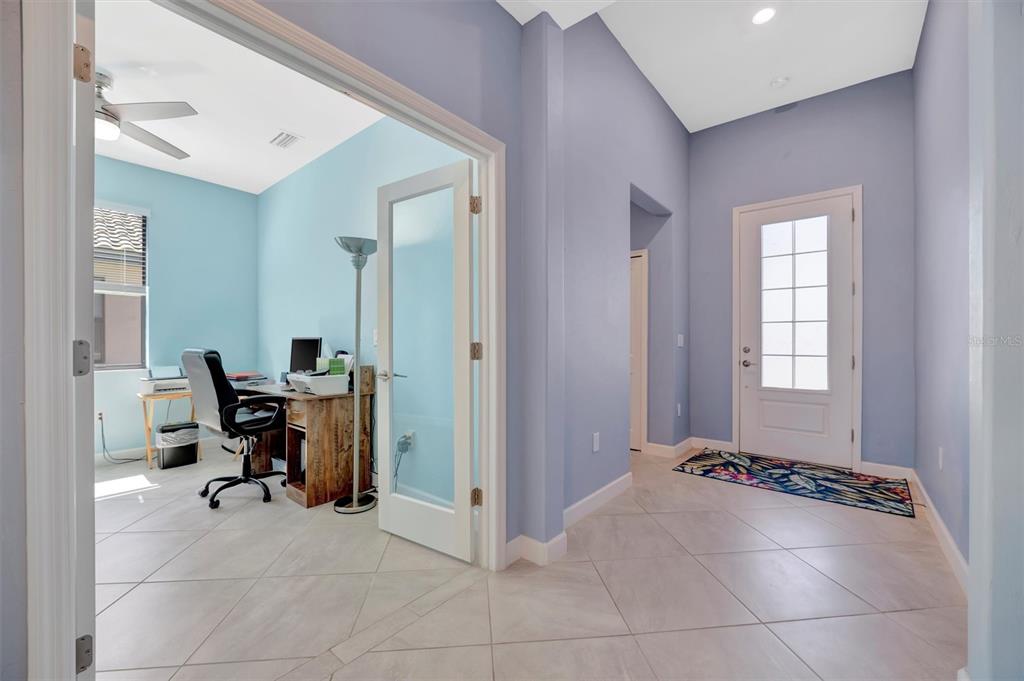 A light blue entryway features tile flooring, a glass-paneled front door, and an adjacent home office — 5317 CORAL REEF WAY, BRADENTON, FL