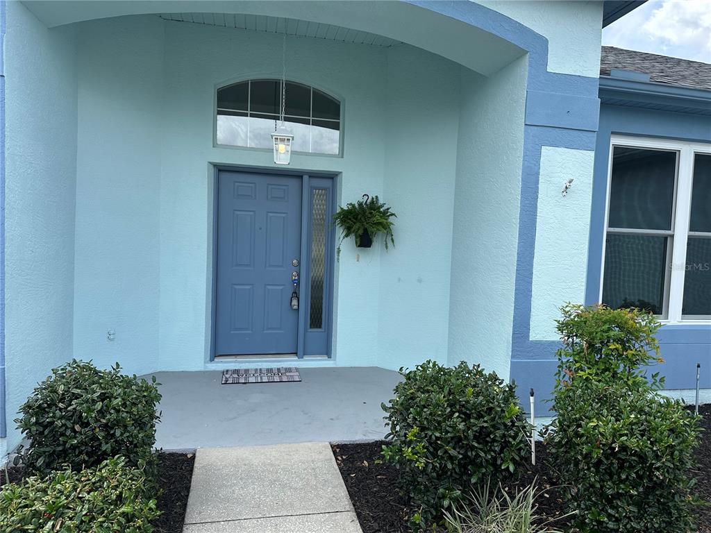 A light blue house exterior features a front door with a sidelight and arched transom — 210 W REXFORD DRIVE, BEVERLY HILLS, FL