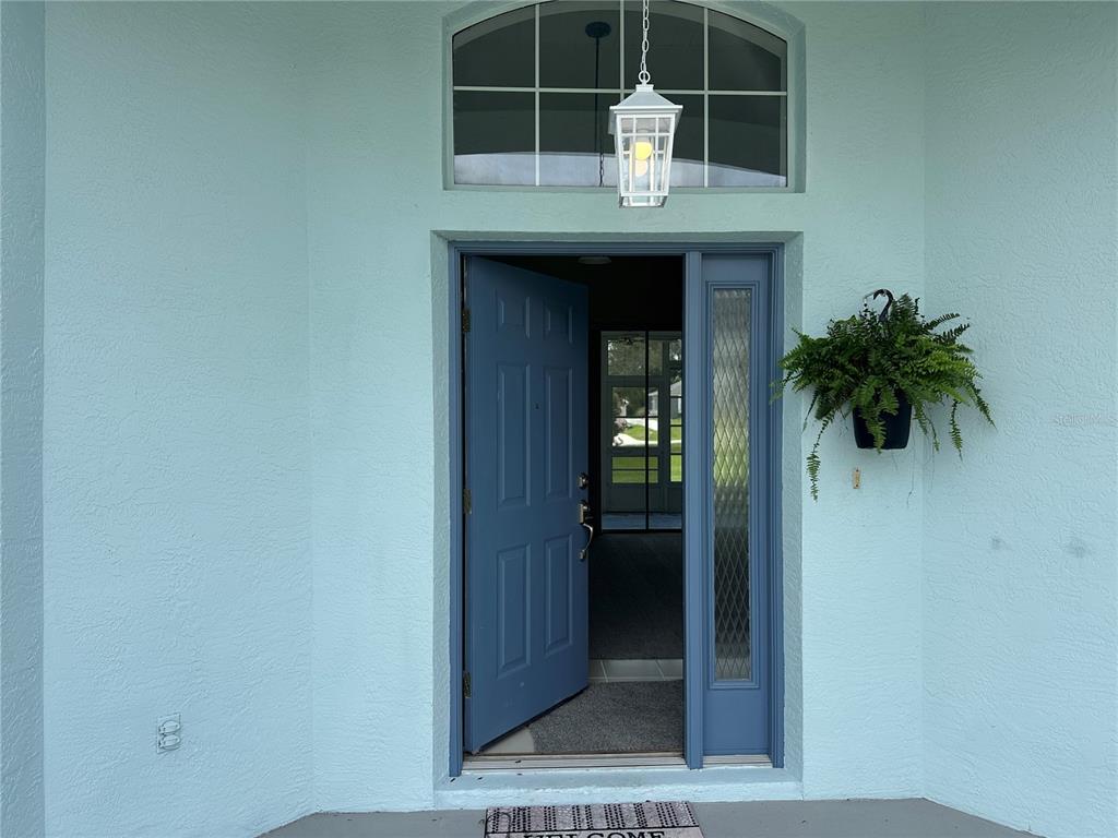 A light blue exterior wall features a blue front door with a side light and transom — 210 W REXFORD DRIVE, BEVERLY HILLS, FL