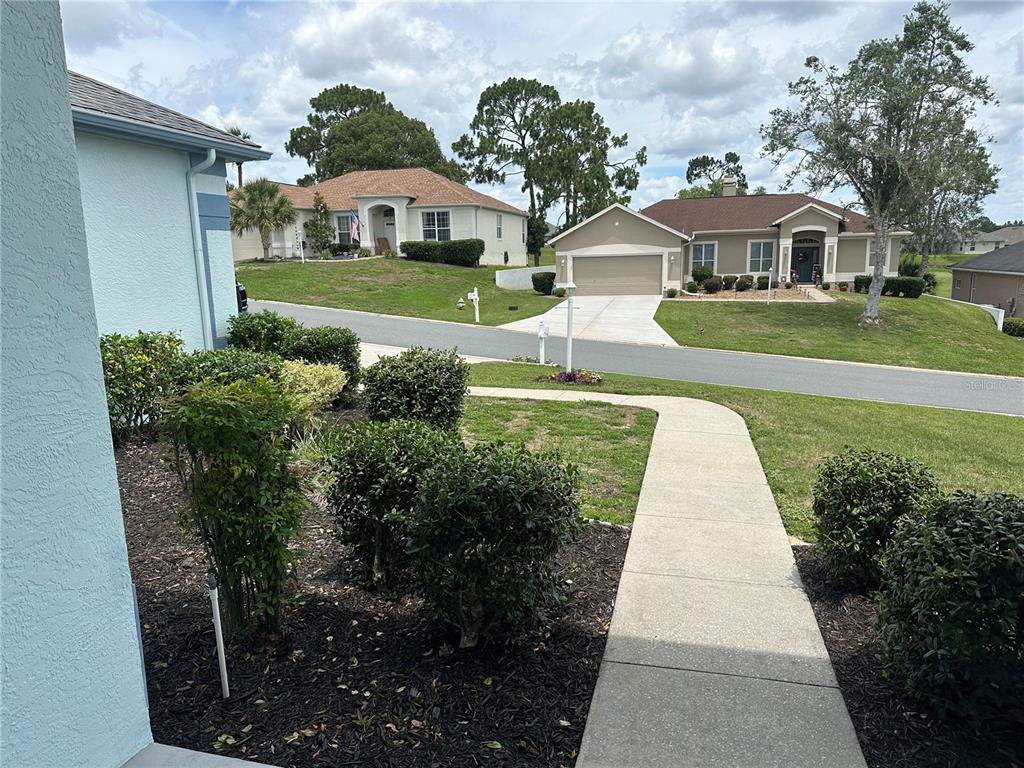 A view of a suburban street with houses, a sidewalk, and landscaped front yards — 210 W REXFORD DRIVE, BEVERLY HILLS, FL