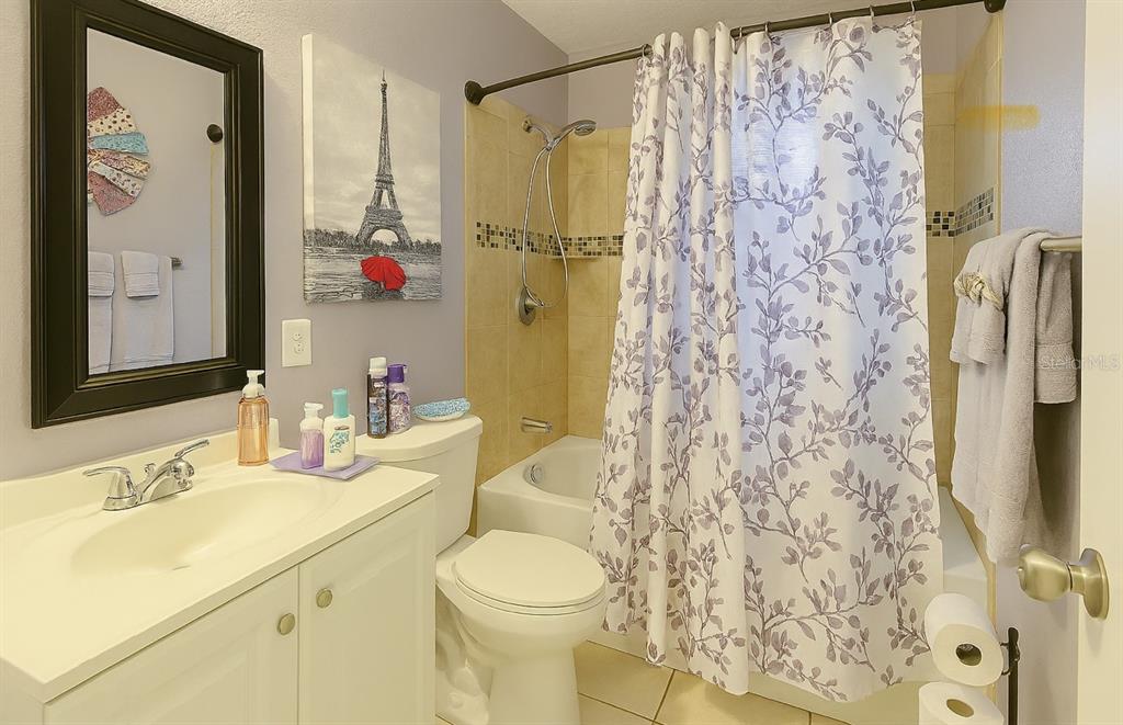 A bathroom features a white vanity, a toilet, and a shower with a floral curtain — 5294 LANETTE STREET, ORLANDO, FL