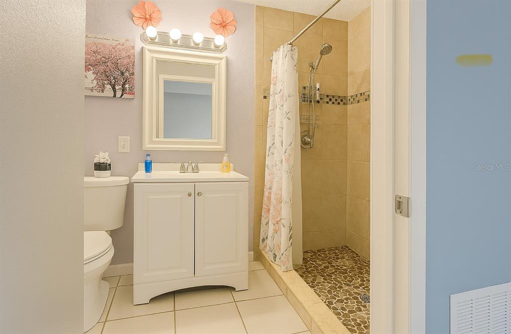 A bathroom features a white vanity, a mirror, a toilet, and a tiled walk-in shower — 5294 LANETTE STREET, ORLANDO, FL