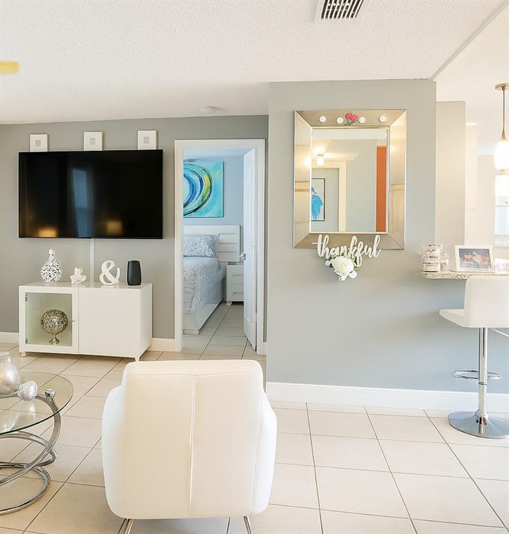 A living room features a wall-mounted television, a white console, and a mirror-adorned accent wall — 5294 LANETTE STREET, ORLANDO, FL
