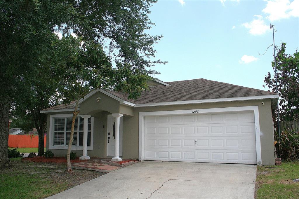 A single-story house with a beige exterior, a two-car garage, and a front porch — 5298 YAUPON STREET, ORLANDO, FL