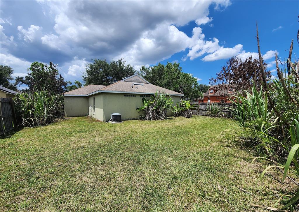 The exterior of a single-story house with a backyard, lawn, and an air conditioning unit — 5298 YAUPON STREET, ORLANDO, FL