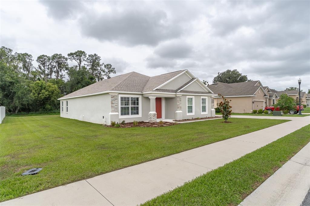 A single-story house with a red front door, stone accents, and a large grassy yard — 344 KISSENGEN PARK DRIVE, BARTOW, FL