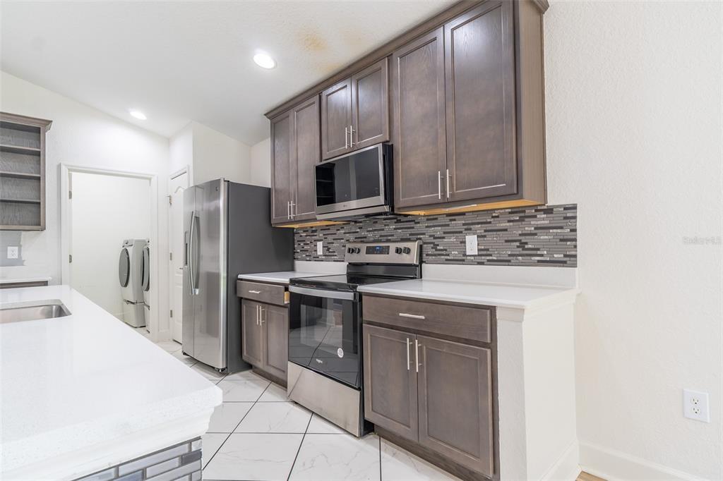 A kitchen features dark wood cabinets, stainless steel appliances, and white countertops — 344 KISSENGEN PARK DRIVE, BARTOW, FL