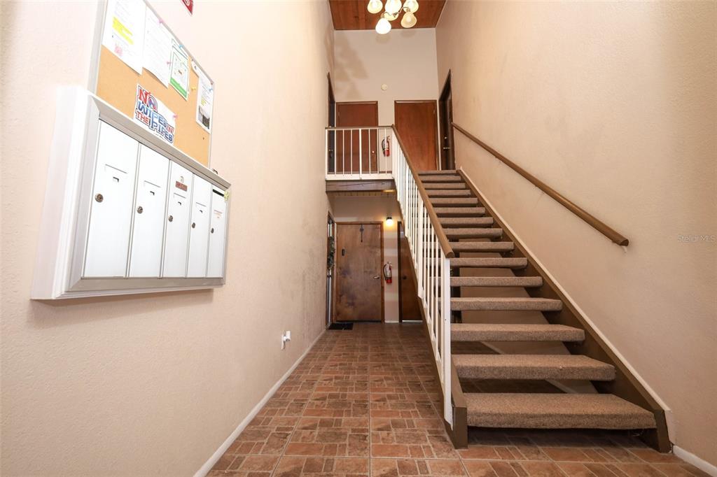 An indoor apartment building entryway features a carpeted staircase, mailboxes, and tiled flooring — 200 MAITLAND AVENUE UNIT 78, ALTAMONTE SPRINGS, FL