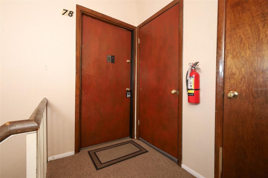 A hallway features two red doors, a fire extinguisher, and a wooden handrail — 200 MAITLAND AVENUE UNIT 78, ALTAMONTE SPRINGS, FL