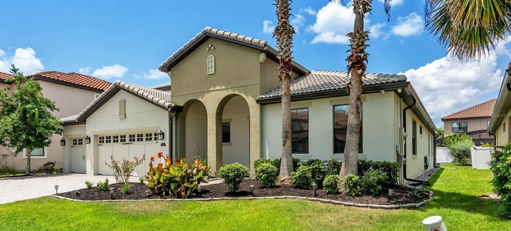 A single-story house with a beige stucco exterior, arched entryway, and a two-car garage — 3814 SHORESIDE DRIVE, KISSIMMEE, FL