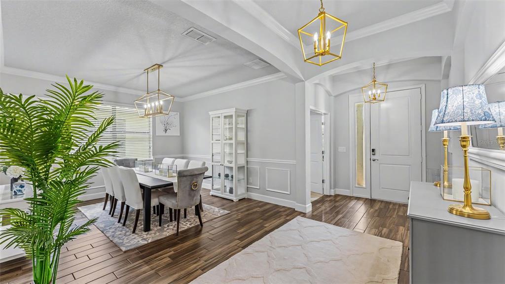 A dining room and entryway feature light gray walls, wood-look flooring, and gold geometric chandeliers — 3814 SHORESIDE DRIVE, KISSIMMEE, FL