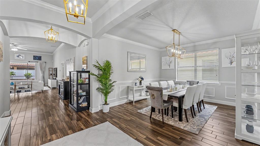A dining room with wood-look tile floors, a rectangular table, and gold geometric light fixtures — 3814 SHORESIDE DRIVE, KISSIMMEE, FL