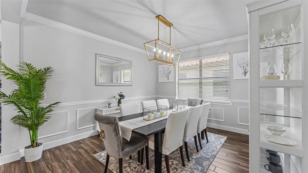 A dining room features a dark table, upholstered chairs, a gold chandelier, and wood flooring — 3814 SHORESIDE DRIVE, KISSIMMEE, FL
