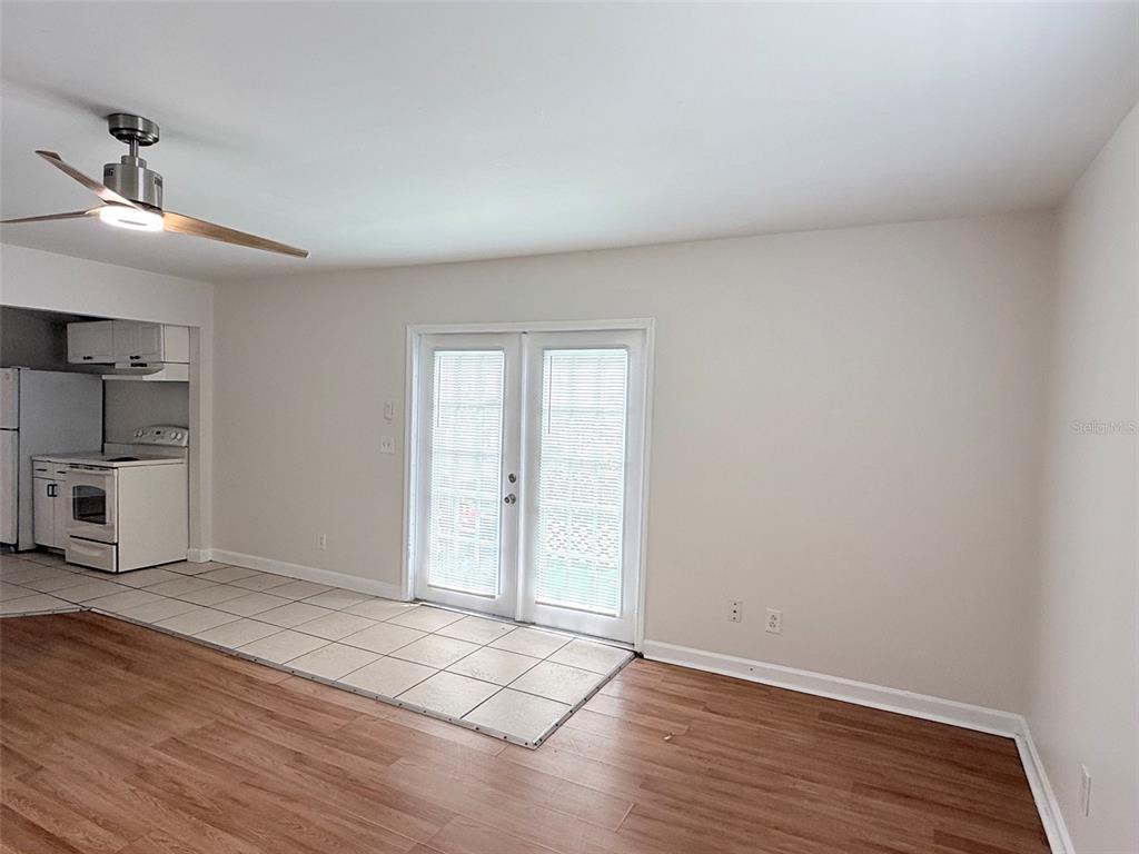 A room with wood-look flooring, a tiled kitchen area, and French doors leading outside — 3611 2ND AVENUE S, ST PETERSBURG, FL