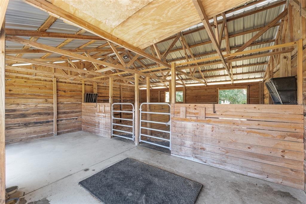 An indoor horse stable with two stalls, wooden walls, and a concrete floor — 9128 NW 238TH STREET, ALACHUA, FL