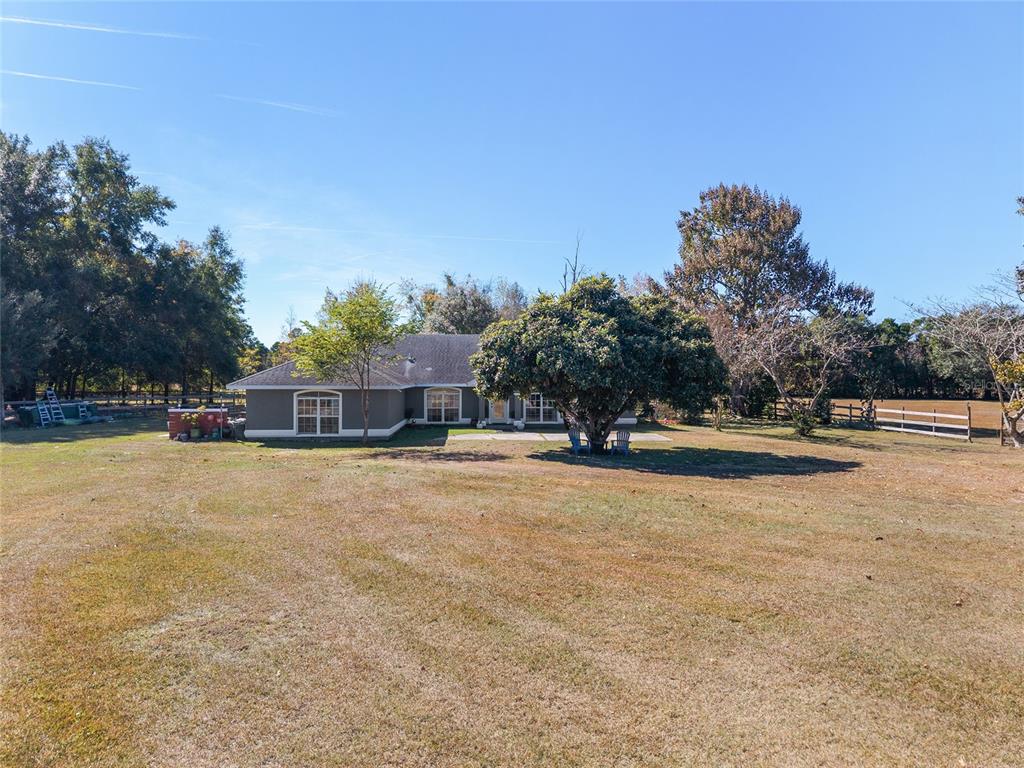 A single-story house with a gray exterior sits on a large, grassy lot — 9128 NW 238TH STREET, ALACHUA, FL
