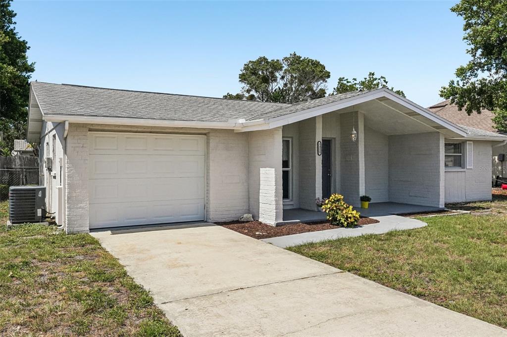 A single-story house with a white brick exterior, a one-car garage, and a covered entryway — 7215 MAYFIELD DRIVE, PORT RICHEY, FL