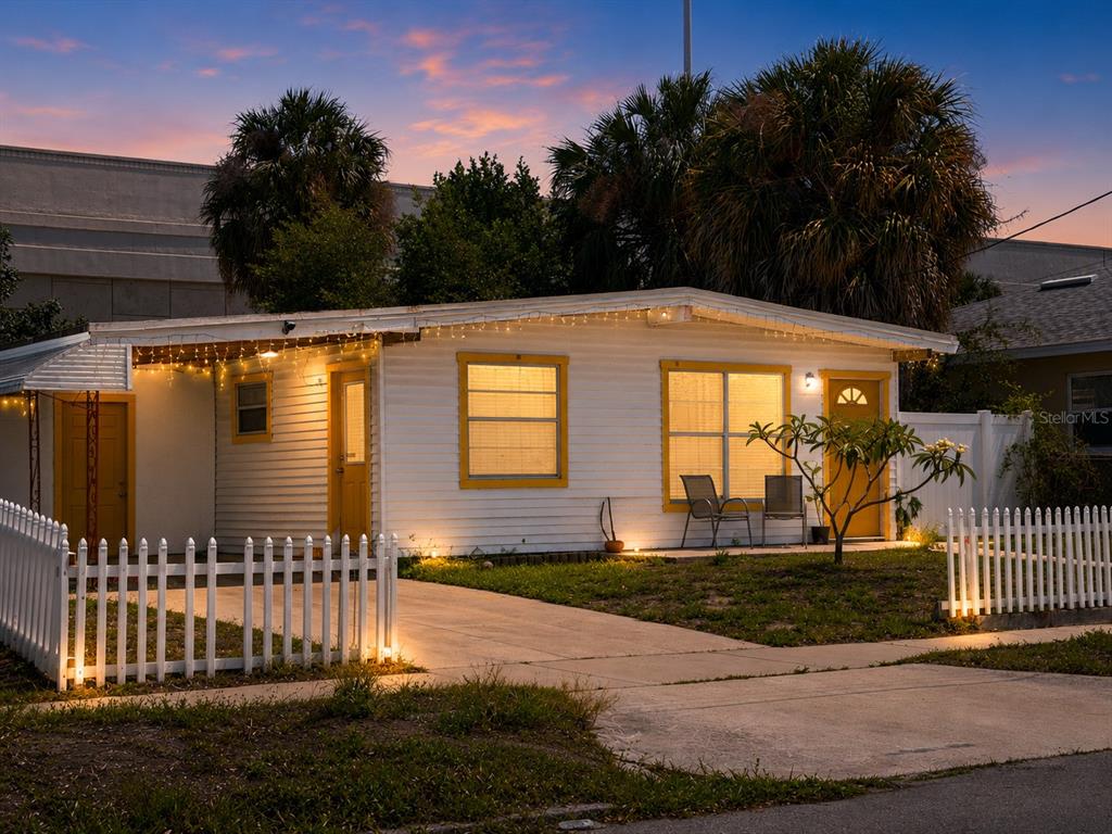 A single-story white house with yellow trim and a white picket fence at dusk — 1541 W LA SALLE STREET, TAMPA, FL