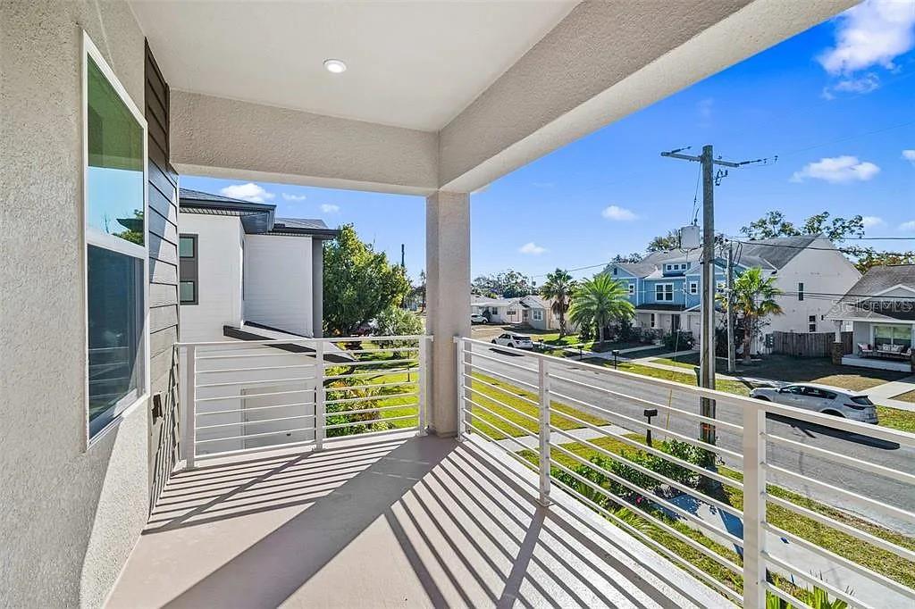 A covered balcony with white railings overlooks a residential street and neighboring houses — 1541 W LA SALLE STREET, TAMPA, FL