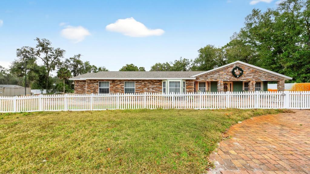 A single-story brick house with a white picket fence and a brick driveway — 746 W WASHINGTON AVENUE W, LAKE HELEN, FL