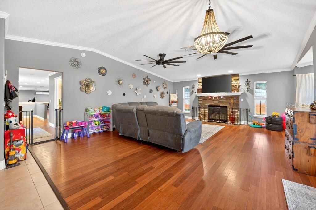 A living room with hardwood floors, a stone fireplace, and a large gray sectional sofa — 746 W WASHINGTON AVENUE W, LAKE HELEN, FL