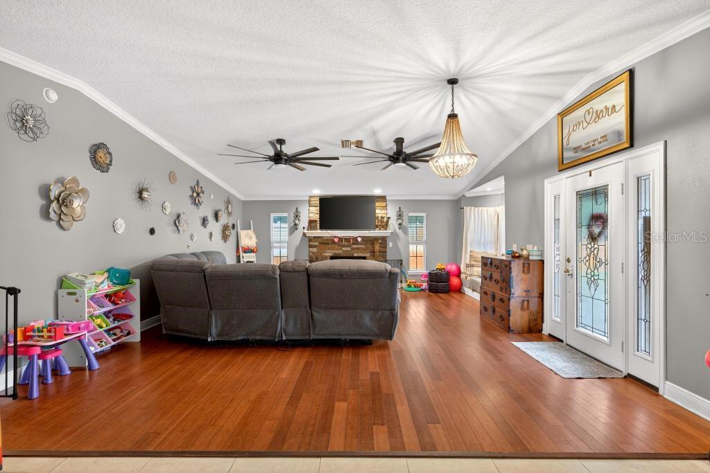 A living room features hardwood floors, a stone fireplace, ceiling fans, and a gray sectional — 746 W WASHINGTON AVENUE W, LAKE HELEN, FL