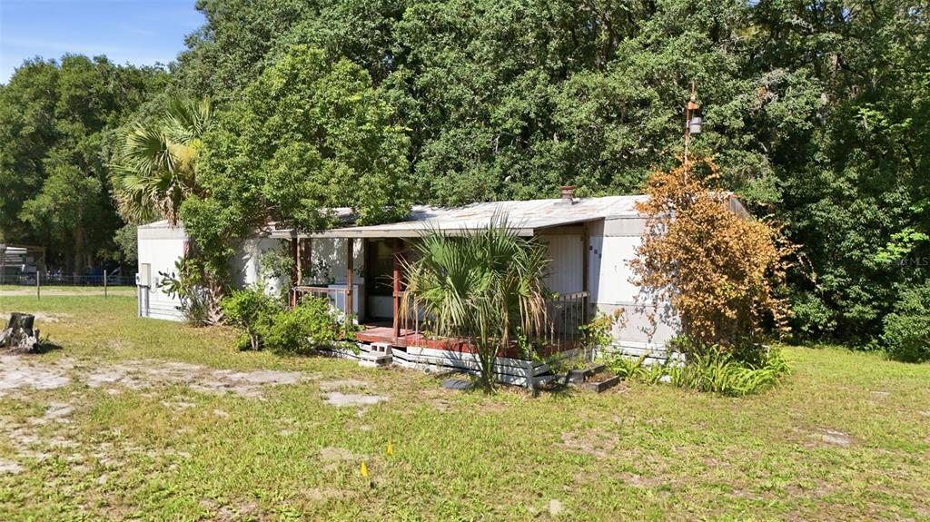 A single-story mobile home with a covered front porch sits on a grassy lot — 37807 DEERWOODS DRIVE, EUSTIS, FL