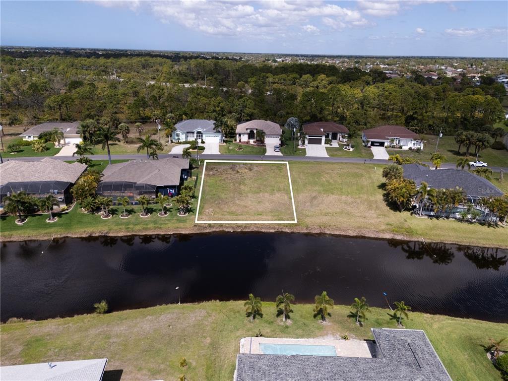 An aerial view shows a vacant residential lot situated between two houses along a canal — 134 WHITE MARSH LANE, ROTONDA WEST, FL