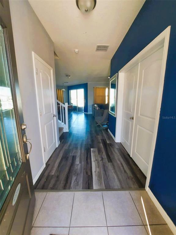 An entryway with tile flooring transitions into a hallway with wood-look floors and blue walls — 11542 BRIGHTON KNOLL LOOP, RIVERVIEW, FL