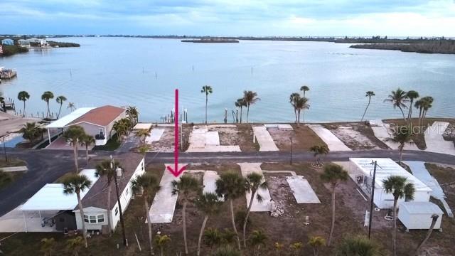 An aerial view shows a waterfront lot with a concrete pad and palm trees — 7500 PARK POINTE DRIVE UNIT 53, ENGLEWOOD, FL