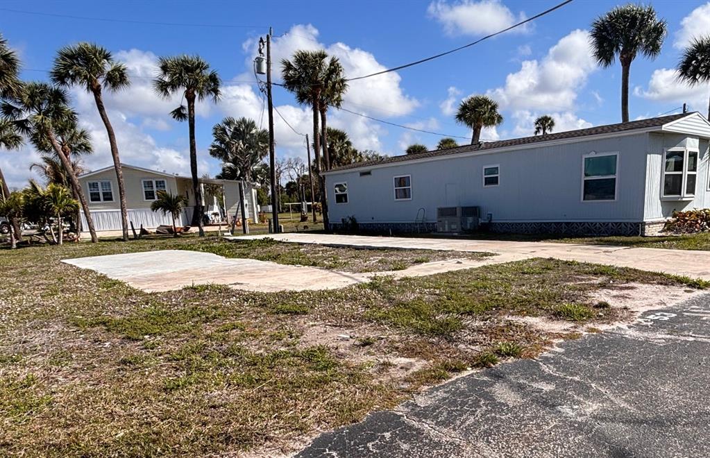 A light blue mobile home sits on a lot with palm trees and concrete pads — 7500 PARK POINTE DRIVE UNIT 53, ENGLEWOOD, FL