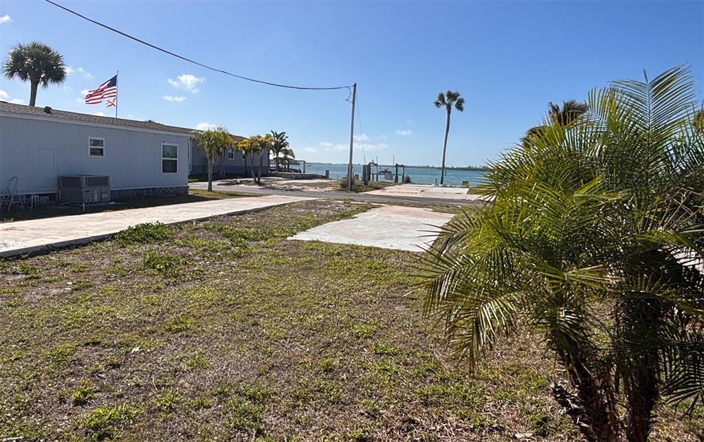 A vacant waterfront lot features a concrete pad next to a neighboring manufactured home — 7500 PARK POINTE DRIVE UNIT 53, ENGLEWOOD, FL